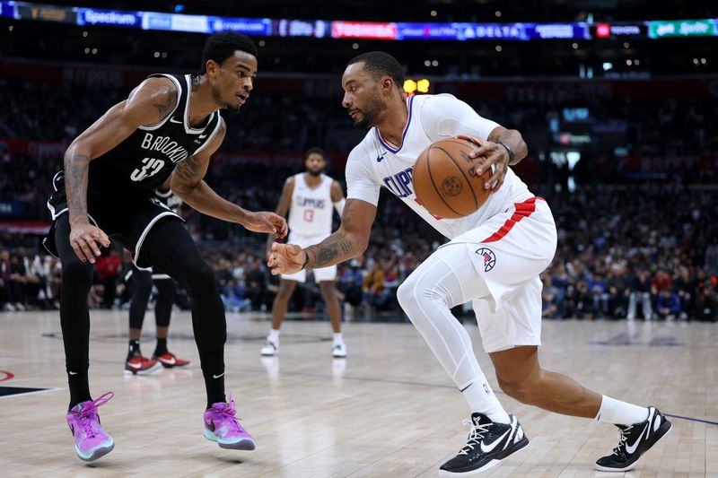 LOS ANGELES, CALIFORNIA - JANUARY 21: Norman Powell #24 of the LA Clippers drives to the basket on Nic Claxton #33 of the Brooklyn Nets during a 125-114 Clippers win at Crypto.com Arena on January 21, 2024 in Los Angeles, California. User is consenting to the terms and conditions of the Getty Images License Agreement. (Photo by Harry How/Getty Images)