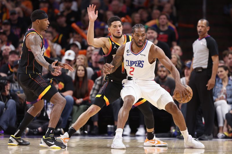 PHOENIX, ARIZONA - APRIL 18: Kawhi Leonard #2 of the LA Clippers handles the ball against Torrey Craig #0 and Devin Booker #1 of the Phoenix Suns during the second half of Game Two of the Western Conference First Round Playoffs at Footprint Center on April 18, 2023 in Phoenix, Arizona. The Suns defeated the Clippers 123-109. NOTE TO USER: User expressly acknowledges and agrees that, by downloading and or using this photograph, User is consenting to the terms and conditions of the Getty Images License Agreement.  (Photo by Christian Petersen/Getty Images)