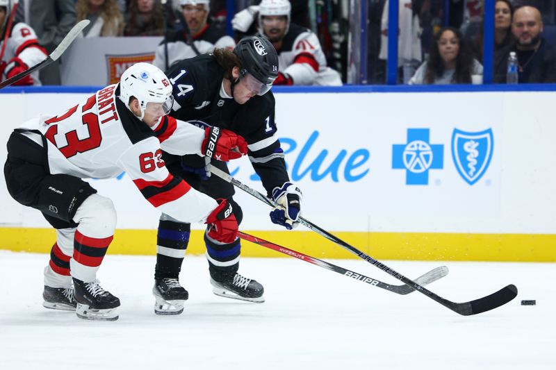 Nov 16, 2024; Tampa, Florida, USA; Tampa Bay Lightning center Conor Geekie (14) and New Jersey Devils left wing Jesper Bratt (63) battle for the puck in the first period at Amalie Arena. Mandatory Credit: Nathan Ray Seebeck-Imagn Images