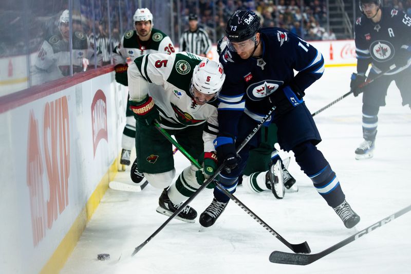 Feb 20, 2024; Winnipeg, Manitoba, CAN; Winnipeg Jets forward Gabriel Vilardi (13) and Minnesota Wild defenseman Jake Middleton (5) fight for the puck the second period at Canada Life Centre. Mandatory Credit: Terrence Lee-USA TODAY Sports