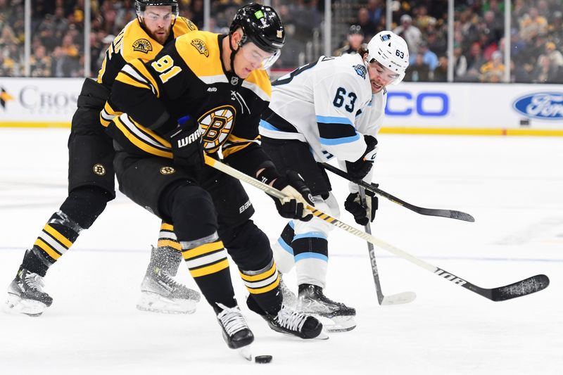 Nov 21, 2024; Boston, Massachusetts, USA;  Boston Bruins defenseman Nikita Zadorov (91) tries to gain control of the puck ahead of Utah Hockey Club left wing Matias Maccelli (63) during the second period at TD Garden. Mandatory Credit: Bob DeChiara-Imagn Images