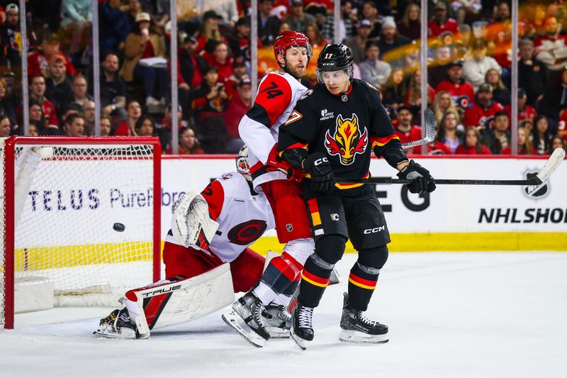 Mar 7, 2026; Calgary, Alberta, CAN; Calgary Flames center Yegor Sharangovich (17) and Carolina Hurricanes defenseman Jaccob Slavin (74) fight for position in front of Carolina Hurricanes goaltender Brandon Bussi (32) during the second period at Scotiabank Saddledome. Mandatory Credit: Sergei Belski-Imagn Images