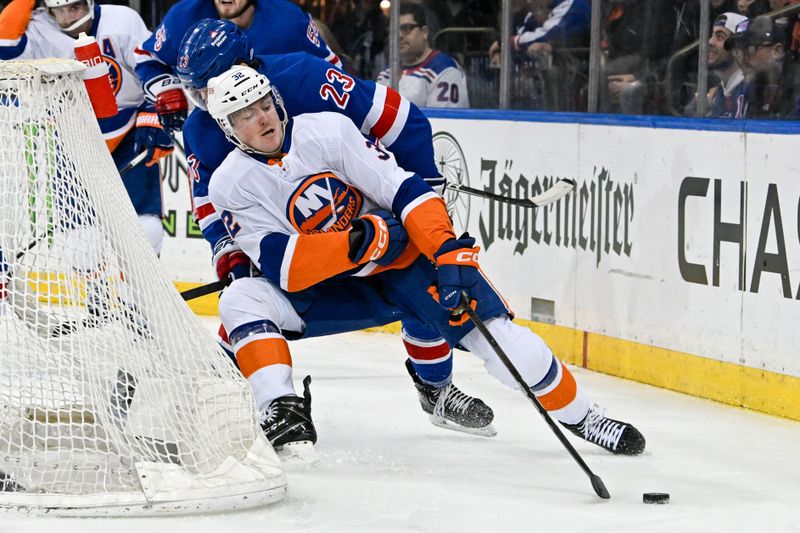 Apr 13, 2024; New York, New York, USA;  New York Islanders center Kyle MacLean (32) skates the puck from behind the net chased by New York Rangers defenseman Adam Fox (23) during the first period at Madison Square Garden. Mandatory Credit: Dennis Schneidler-USA TODAY Sports