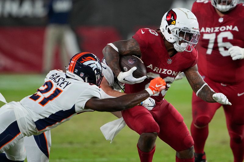 Arizona Cardinals running back Corey Clement, right, runs against Denver Broncos cornerback Essang Bassey during the first half of an NFL preseason football game in Glendale, Ariz., Friday, Aug. 11, 2023. (AP Photo/Matt York)