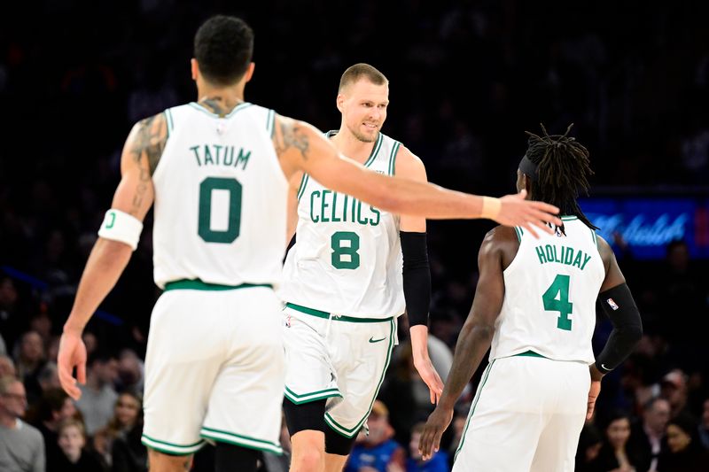 NEW YORK, NEW YORK - FEBRUARY 24:  Kristaps Porzingis #8 of the Boston Celtics is congratulated by Jrue Holiday #4 and Jayson Tatum #0 after scoring a basket against the New York Knicks during the second half at Madison Square Garden on February 24, 2024 in New York City. NOTE TO USER: User expressly acknowledges and agrees that, by downloading and or using this photograph, User is consenting to the terms and conditions of the Getty Images License Agreement. (Photo by Steven Ryan/Getty Images)