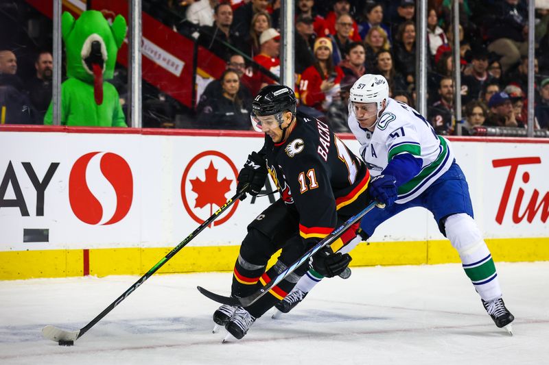 Dec 31, 2024; Calgary, Alberta, CAN; Calgary Flames center Mikael Backlund (11) and Vancouver Canucks defenseman Tyler Myers (57) battles for the puck during the second period at Scotiabank Saddledome. Mandatory Credit: Sergei Belski-Imagn Images