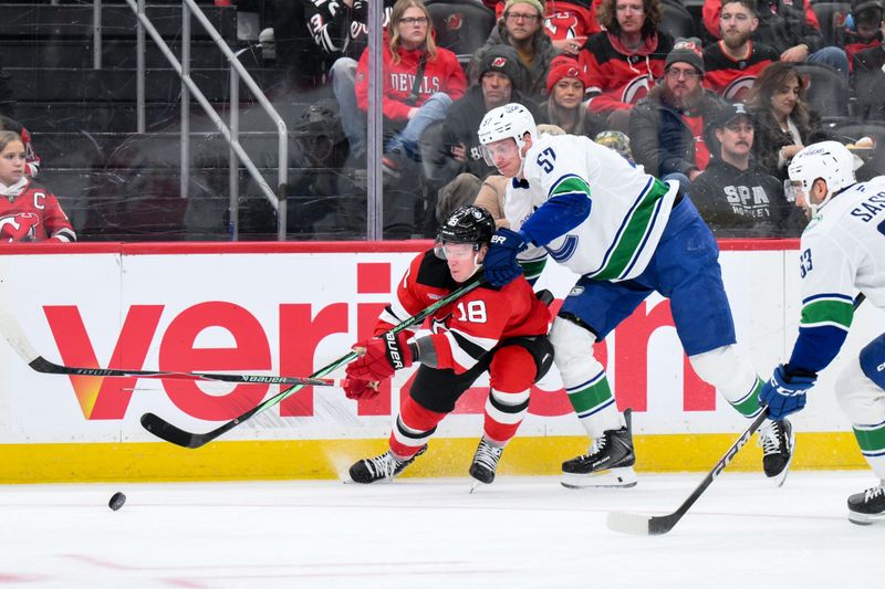Dec 14, 2025; Newark, New Jersey, USA; New Jersey Devils left wing Ondrej Palat (18) competes for the puck against Vancouver Canucks defenseman Tyler Myers (57) during the first period at Prudential Center. Mandatory Credit: John Jones-Imagn Images