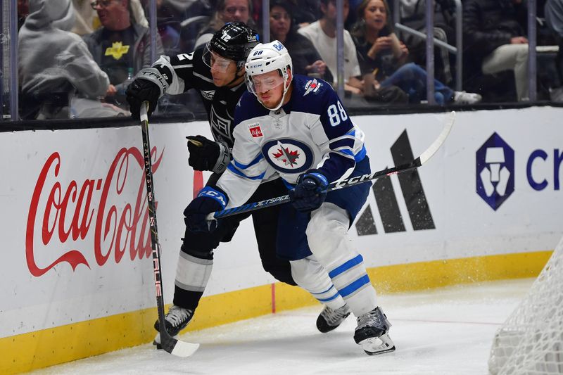 Dec 13, 2023; Los Angeles, California, USA; Winnipeg Jets defenseman Nate Schmidt (88) plays for the puck against Los Angeles Kings left wing Trevor Moore (12) during the second period at Crypto.com Arena. Mandatory Credit: Gary A. Vasquez-USA TODAY Sports