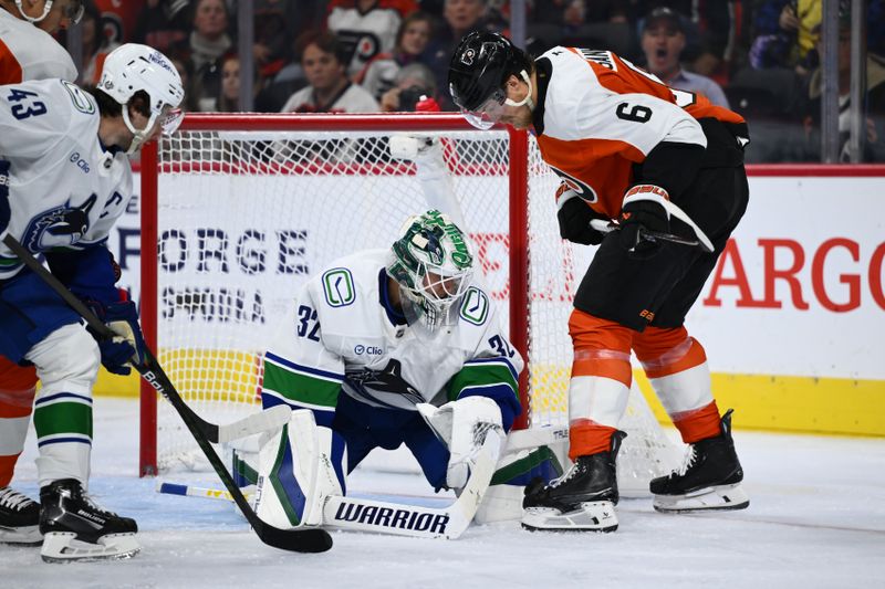 Oct 19, 2024; Philadelphia, Pennsylvania, USA; Vancouver Canucks goalie Kevin Lankinen (32) reaches for a loose puck against Philadelphia Flyers defenseman Travis Sanheim (6) in the second period at Wells Fargo Center. Mandatory Credit: Kyle Ross-Imagn Images