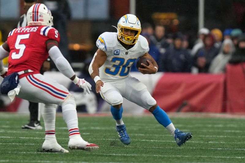 Los Angeles Chargers running back Austin Ekeler (30) eludes New England Patriots safety Jabrill Peppers (5) during the first half of an NFL football game, Sunday, Dec. 3, 2023, in Foxborough, Mass. (AP Photo/Steven Senne)