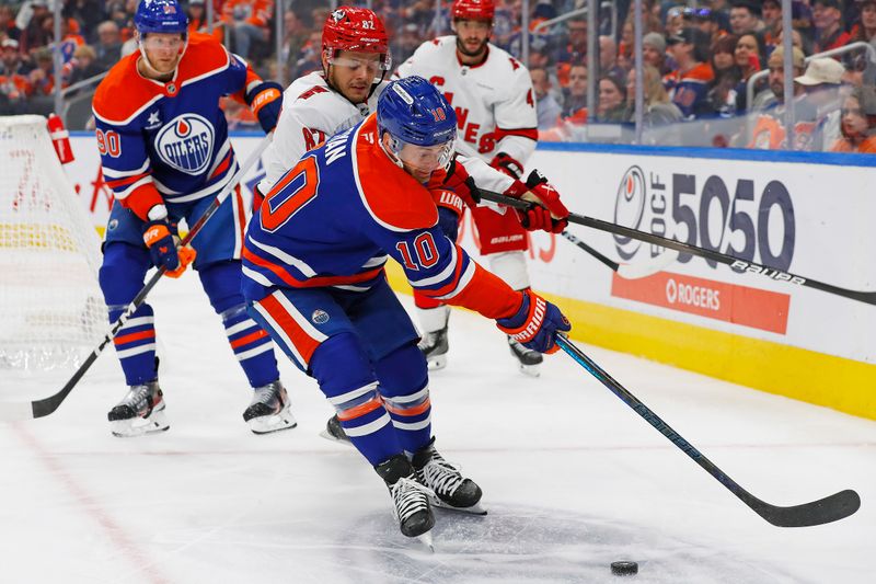 Oct 22, 2024; Edmonton, Alberta, CAN; Edmonton Oilers forward Derek Ryan (10) and Carolina Hurricanes forward Jesperi Kotkaniemi (82) battle along the boards for a loose puck  during the third period at Rogers Place. Mandatory Credit: Perry Nelson-Imagn Images