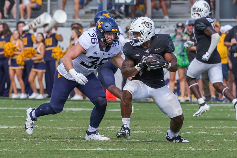 Oct 28, 2023; Orlando, Florida, USA; West Virginia Mountaineers linebacker Caden Biser (36) moves in for the tackle against UCF Knights running back RJ Harvey (7) during the second half at FBC Mortgage Stadium. Mandatory Credit: Mike Watters-USA TODAY Sports