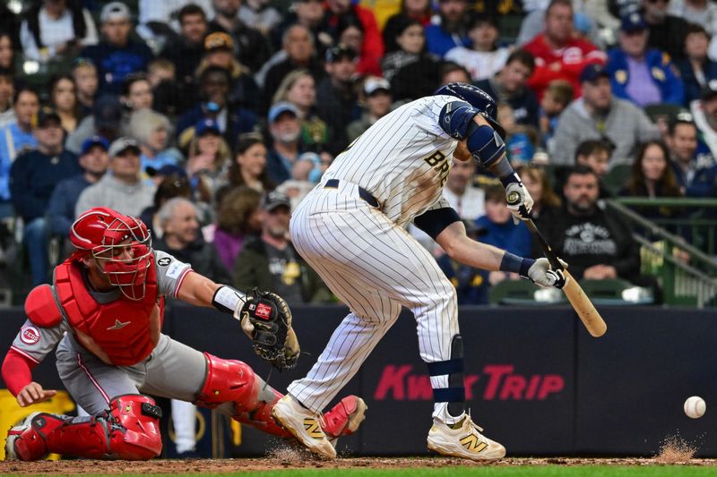 Apr 6, 2025; Milwaukee, Wisconsin, USA;  Milwaukee Brewers third baseman Oliver Dunn (15) drives in a run with a squeeze bunt in the fourth inning as Cincinnati Reds catcher Austin Wynns (38) looks on at American Family Field. Mandatory Credit: Benny Sieu-Imagn Images