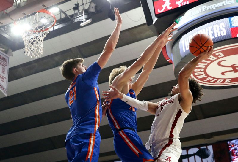 Feb 21, 2024; Tuscaloosa, Alabama, USA;  Florida Gators center Alex Condon (21) and forward Thomas Haugh (10) attempt to block a shot by Alabama Crimson Tide guard Mark Sears (1) at Coleman Coliseum. Mandatory Credit: Gary Cosby Jr.-USA TODAY Sports