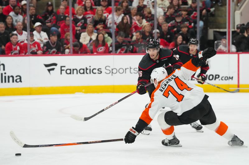 Oct 11, 2025; Raleigh, North Carolina, USA;  Carolina Hurricanes defenseman Sean Walker (26) gets the pass away against Philadelphia Flyers right wing Owen Tippett (74) during the first period at Lenovo Center. Mandatory Credit: James Guillory-Imagn Images