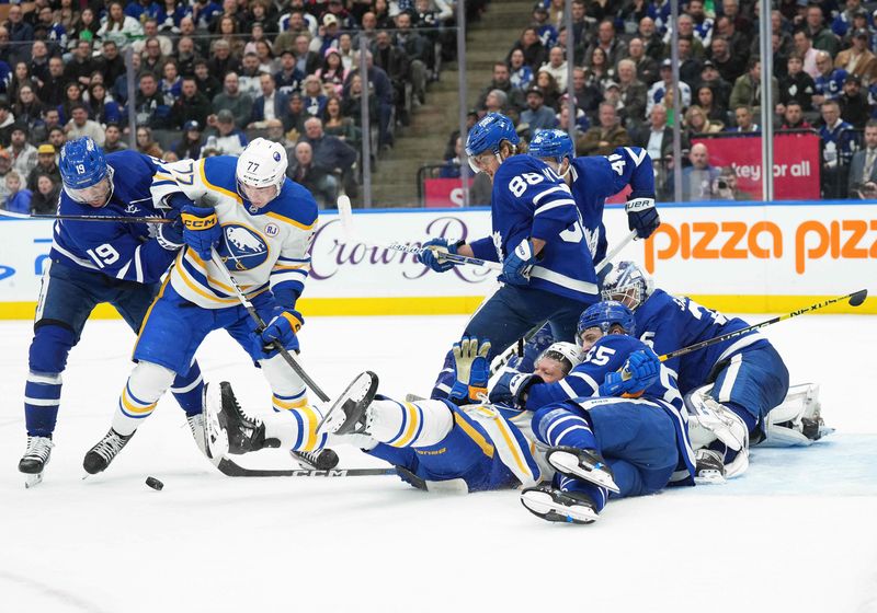 Mar 6, 2024; Toronto, Ontario, CAN; Buffalo Sabres right wing JJ Peterka (77) battles for the puck with Toronto Maple Leafs center Calle Jarnkrok (19) during the second period at Scotiabank Arena. Mandatory Credit: Nick Turchiaro-USA TODAY Sports