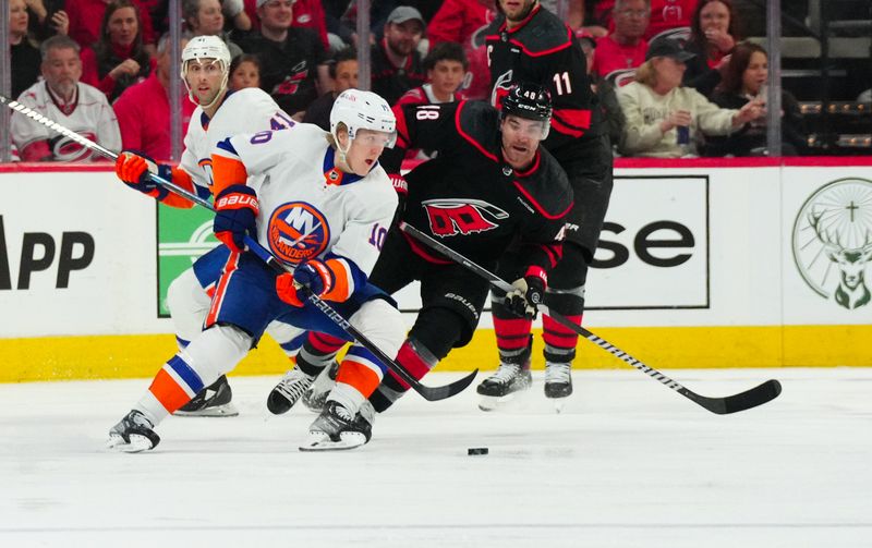 Apr 20, 2024; Raleigh, North Carolina, USA; New York Islanders right wing Simon Holmstrom (10) skates with the puck past Carolina Hurricanes left wing Jordan Martinook (48) during the third period in game one of the first round of the 2024 Stanley Cup Playoffs at PNC Arena. Mandatory Credit: James Guillory-USA TODAY Sports