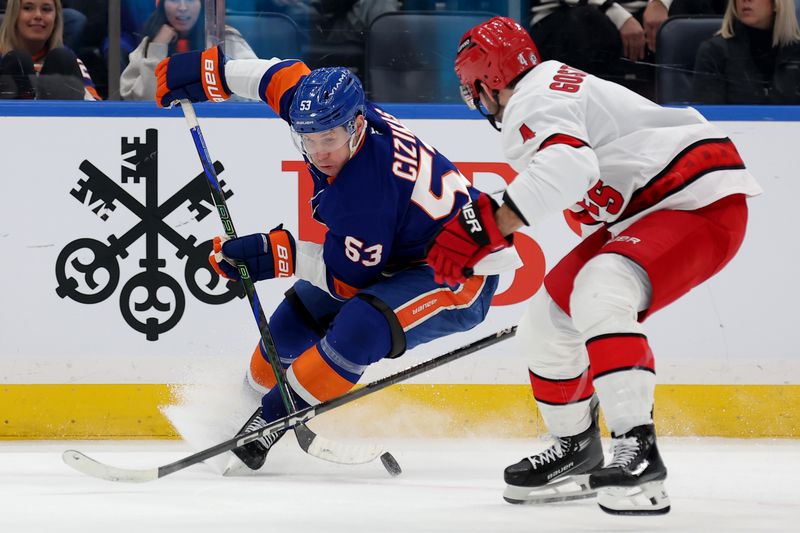 Jan 25, 2025; Elmont, New York, USA; New York Islanders center Casey Cizikas (53) fights for the puck against Carolina Hurricanes defenseman Shayne Gostisbehere (4) during the first period at UBS Arena. Mandatory Credit: Brad Penner-Imagn Images