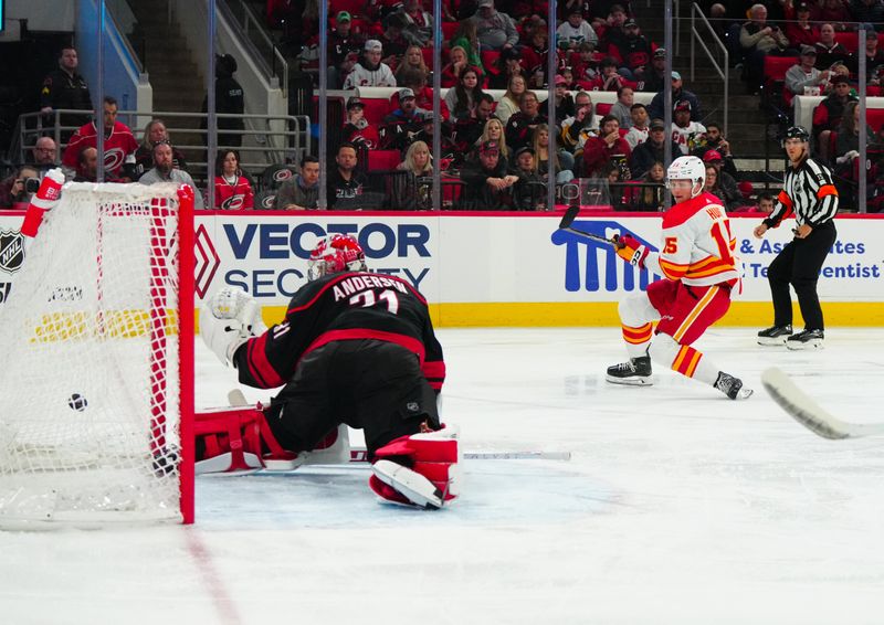 Mar 10, 2024; Raleigh, North Carolina, USA;  Calgary Flames left wing Dryden Hunt (15) scores a goal past Carolina Hurricanes goaltender Frederik Andersen (31) during the second period at PNC Arena. Mandatory Credit: James Guillory-USA TODAY Sports