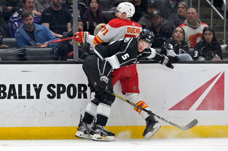 Apr 11, 2024; Los Angeles, California, USA;  Los Angeles Kings defenseman Andreas Englund (5) checks Calgary Flames right wing Walker Duehr (71) into the boards in the first period at Crypto.com Arena. Mandatory Credit: Jayne Kamin-Oncea-USA TODAY Sports