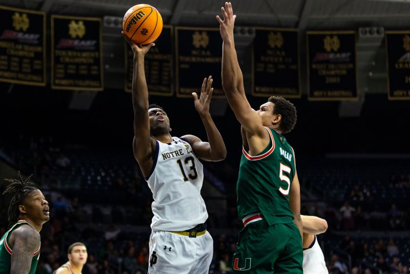 Jan 13, 2026; South Bend, Indiana, USA;  Notre Dame Fighting Irish guard Sir Mohammed (13) drives as Miami (FL) Hurricanes forward Malik Reneau (5) defends  during the first half at Purcell Pavilion at the Joyce Center. Mandatory Credit: Michael Caterina-Imagn Images