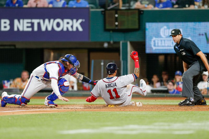 May 15, 2023; Arlington, Texas, USA; Atlanta Braves shortstop Orlando Arcia (11) slides in under a tag by Texas Rangers catcher Jonah Heim (28) during the fifth inning at Globe Life Field. Mandatory Credit: Andrew Dieb-USA TODAY Sports