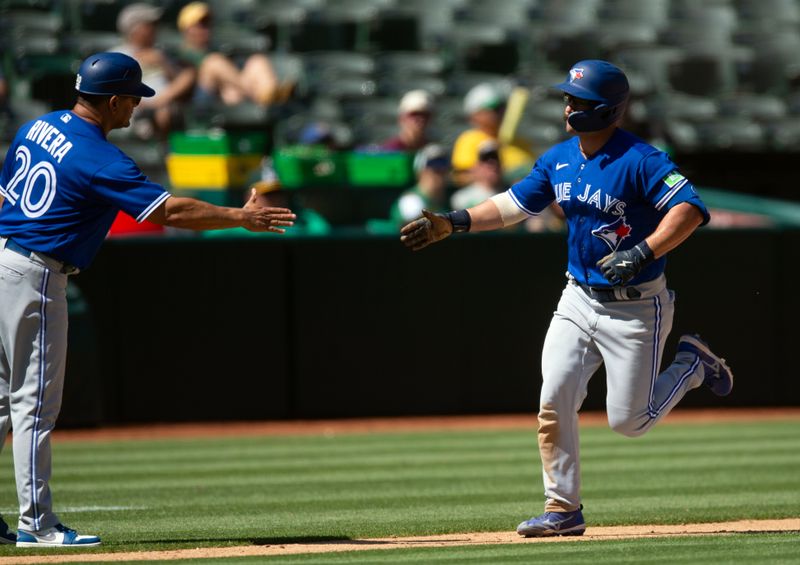 Sep 6, 2023; Oakland, California, USA; Toronto Blue Jays second baseman Davis Schneider (right) is greeted by third base coach Luis Rivera (20) after hitting a solo home run against the Oakland Athletics during the eighth inning at Oakland-Alameda County Coliseum. Mandatory Credit: D. Ross Cameron-USA TODAY Sports