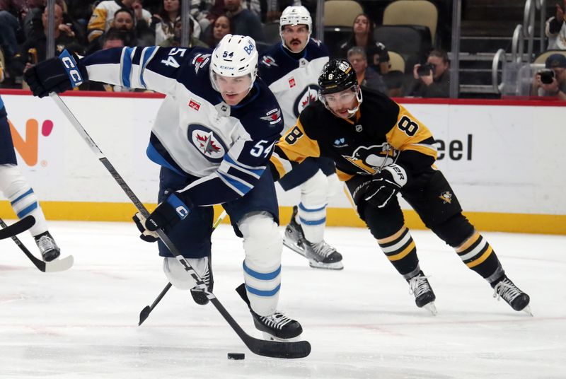 Nov 22, 2024; Pittsburgh, Pennsylvania, USA; Winnipeg Jets defenseman Dylan Samberg (54) clears the puck ahead of Pittsburgh Penguins left wing Michael Bunting (8) during the third period at PPG Paints Arena. Mandatory Credit: Charles LeClaire-Imagn Images