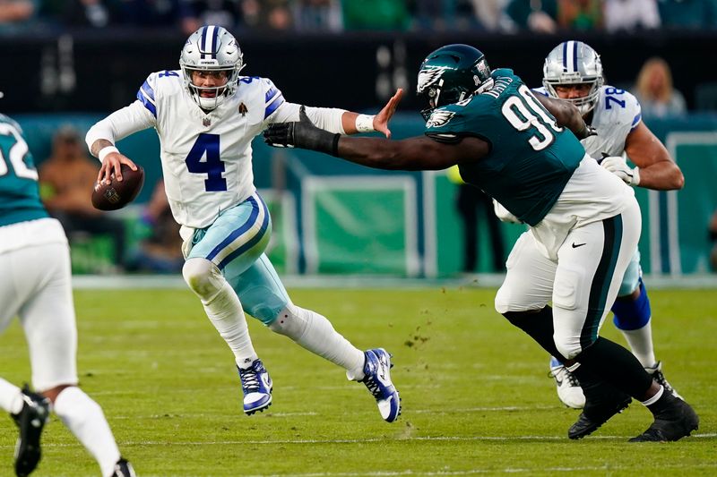 Dallas Cowboys quarterback Dak Prescott (4) runs with the ball under pressure from Philadelphia Eagles defensive tackle Jordan Davis (90) during the first half of an NFL football game Sunday, Nov. 5, 2023, in Philadelphia. (AP Photo/Chris Szagola)