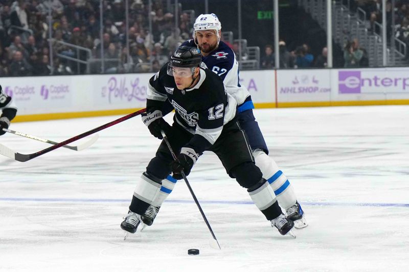 Nov 27, 2024; Los Angeles, California, USA; LA Kings left wing Trevor Moore (12) skates with the puck against Winnipeg Jets right wing Nino Niederreiter (62) in the second period at Crypto.com Arena. Mandatory Credit: Kirby Lee-Imagn Images