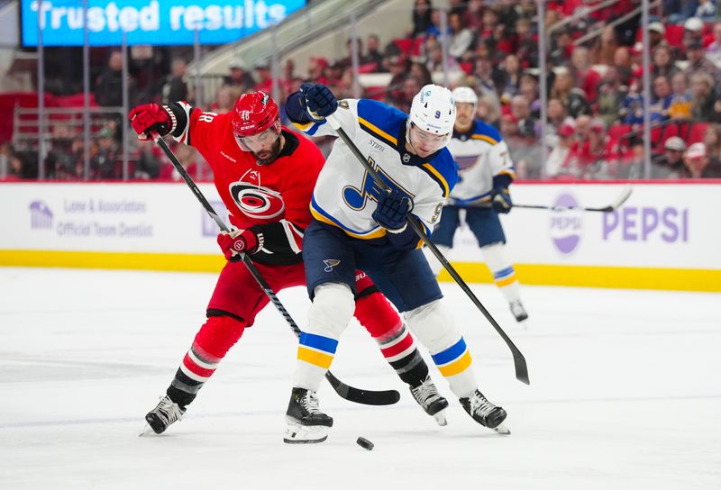 Nov 17, 2024; Raleigh, North Carolina, USA;  St. Louis Blues center Alexandre Texier (9) battles for the puck against Carolina Hurricanes left wing Jordan Martinook (48) during the first period at Lenovo Center. Mandatory Credit: James Guillory-Imagn Images