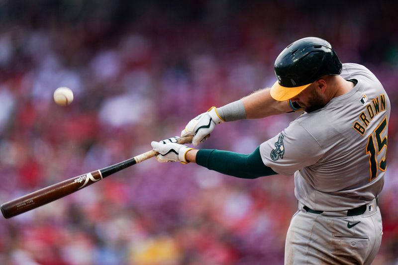 Aug 29, 2024; Cincinnati, Ohio, USA;  Oakland Athletics first base Seth Brown (15) hits the ball during the second inning of the MLB game between the Cincinnati Reds and Oakland Athletics, Thursday, Aug. 29, 2024, at Cintas Center in Cincinnati. Mandatory Credit: Frank Bowen IV/The Cincinnati Enquirer-USA TODAY Sports