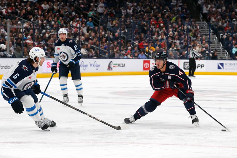 Nov 1, 2024; Columbus, Ohio, USA; Columbus Blue Jackets center Cole Sillinger (4) looks to pass as Winnipeg Jets defenseman Colin Miller (6) defends  during the second period at Nationwide Arena. Mandatory Credit: Russell LaBounty-Imagn Images