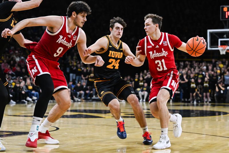 Feb 17, 2026; Iowa City, Iowa, USA; Nebraska Cornhuskers guard Cale Jacobsen (31) controls the ball as Iowa Hawkeyes guard Tate Sage (24) defends and forward Berke Buyuktuncel (9) looks on during the first half at Carver-Hawkeye Arena. Mandatory Credit: Jeffrey Becker-Imagn Images
