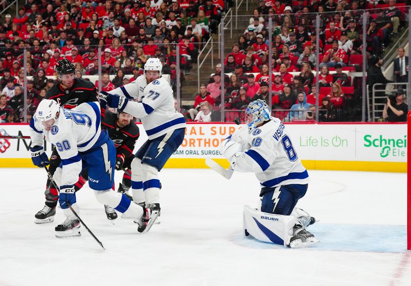 Oct 11, 2024; Raleigh, North Carolina, USA;  Tampa Bay Lightning goaltender Andrei Vasilevskiy (88) stops the shot next to defenseman Victor Hedman (77) and defenseman Janis Moser (90) during the third period t PNC Arena. Mandatory Credit: James Guillory-Imagn Images