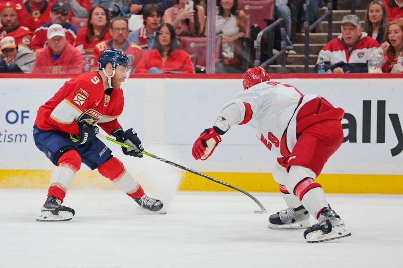May 26, 2025; Sunrise, Florida, USA; Florida Panthers center Sam Bennett (9) and Carolina Hurricanes defenseman Dmitry Orlov (7) race for the puck during the third period in game four of the Eastern Conference Final of the 2025 Stanley Cup Playoffs at Amerant Bank Arena. Mandatory Credit: Sam Navarro-Imagn Images