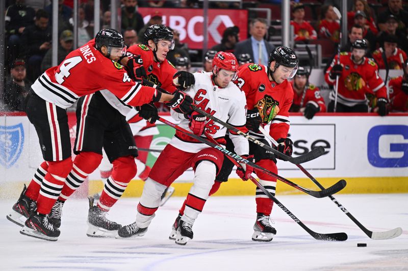 Apr 14, 2024; Chicago, Illinois, USA;  Chicago Blackhawks defenseman Seth Jones (4) and defenseman Alex Vlasic (72) and forward Philipp Kurashev (23) team up to take the puck away from Carolina Hurricanes forward Sebastian Aho (20) in the second period at United Center. Mandatory Credit: Jamie Sabau-USA TODAY Sports