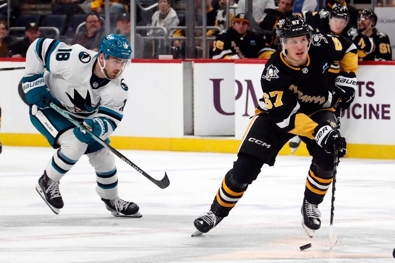 Mar 14, 2024; Pittsburgh, Pennsylvania, USA; Pittsburgh Penguins right wing Rickard Rakell (67) skates with the puck ahead of San Jose Sharks right wing Filip Zadina (18) during the third period at PPG Paints Arena. Pittsburgh won 6-3. Mandatory Credit: Charles LeClaire-USA TODAY Sports