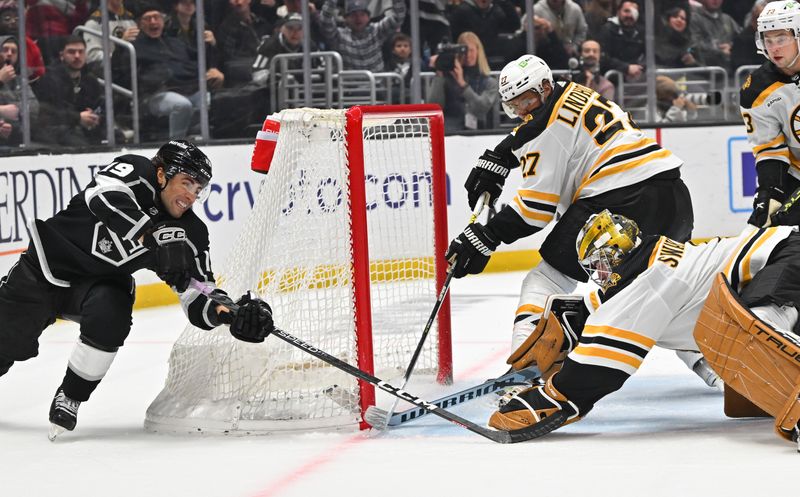 Jan 5, 2023; Los Angeles, California, USA;  Los Angeles Kings right wing Adrian Kempe (9) reaches for the puck as Boston Bruins defenseman Hampus Lindholm (27) assists Boston Bruins goaltender Jeremy Swayman (1) defending in the third period at Crypto.com Arena. Mandatory Credit: Jayne Kamin-Oncea-USA TODAY Sports