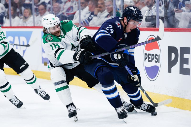 May 7, 2025; Winnipeg, Manitoba, CAN; Winnipeg Jets defenseman Hayden Fleury (24) shields the puck from Dallas Stars forward Sam Steel (18) during the first period in game one of the second round of the 2025 Stanley Cup Playoffs at Canada Life Centre. Mandatory Credit: Terrence Lee-Imagn Images
