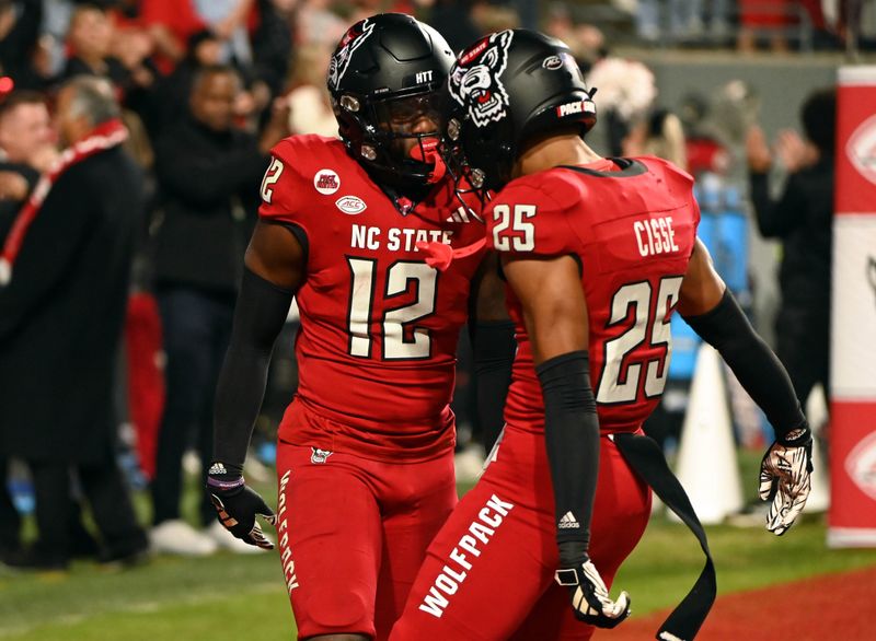 Nov 4, 2023; Raleigh, North Carolina, USA; North Carolina State Wolfpack safety Devan Boykin (12) is greeted by teammate Brandon Cisse (25) after an interception during the second half against the Miami Hurricanes at Carter-Finley Stadium.  Mandatory Credit: Rob Kinnan-USA TODAY Sports