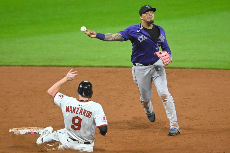 Jul 28, 2025; Cleveland, Ohio, USA; Colorado Rockies shortstop Orlando Arcia (11) turns a double play beside Cleveland Guardians designated hitter Kyle Manzardo (9) in the ninth inning at Progressive Field. Mandatory Credit: David Richard-Imagn Images