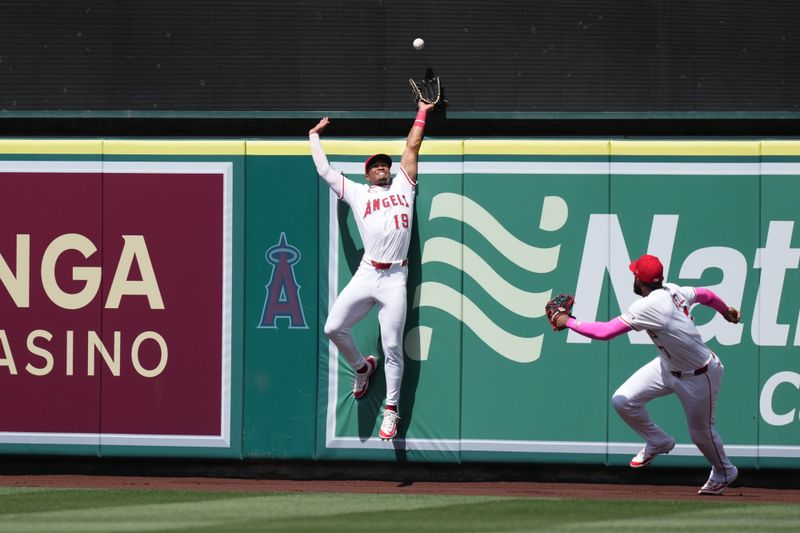 May 11, 2025; Anaheim, California, USA; Los Angeles Angels center fielder Kyren Paris (19) leaps at the outfield wall in an attempt to catch a two-run home run by Baltimore Orioles shortstop Gunnar Henderson (not pictured) as Angels right fielder Jo Adell (7) watches in the sixth inning at Angel Stadium. Mandatory Credit: Kirby Lee-Imagn Images