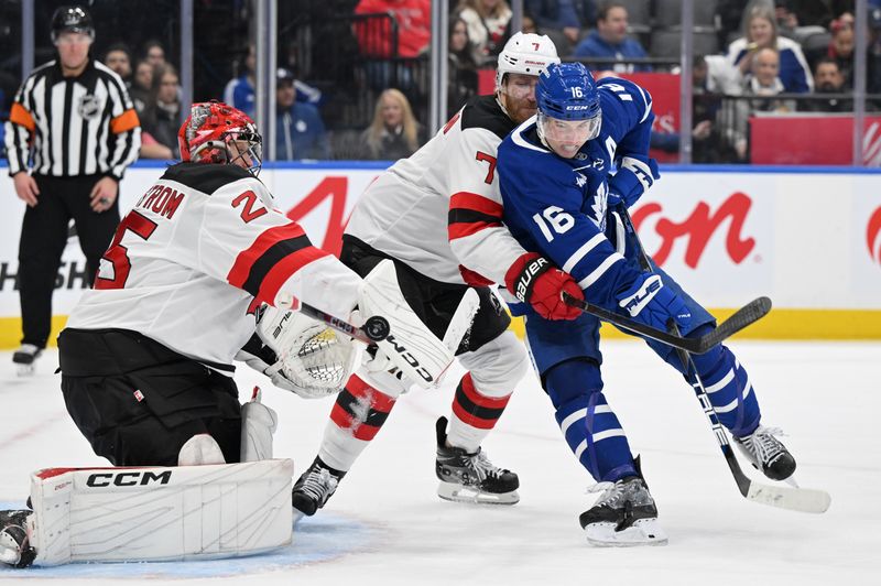 Jan 16, 2025; Toronto, Ontario, CAN;  New Jersey Devils goalie Jacob Markstrom (25) makes a save as defenseman Dougie Hamilton (7) covers Toronto Maple Leafs forward Mitch Marner (16) in the third period at Scotiabank Arena. Mandatory Credit: Dan Hamilton-Imagn Images