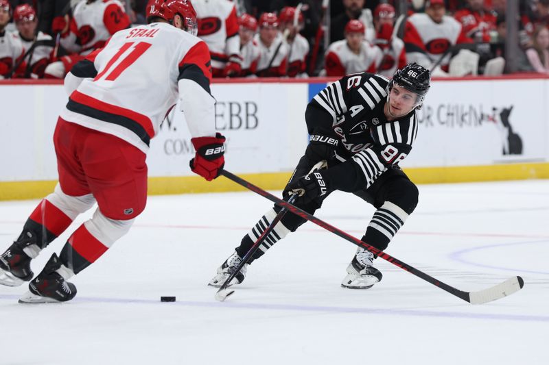 Jan 17, 2026; Newark, New Jersey, USA; New Jersey Devils center Jack Hughes (86) makes a pass as Carolina Hurricanes center Jordan Staal (11) defends during the second period at Prudential Center. Mandatory Credit: Thomas Salus-Imagn Images