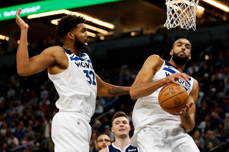 MINNEAPOLIS, MINNESOTA - NOVEMBER 01: Rudy Gobert #27 of the Minnesota Timberwolves rebounds the ball as Karl-Anthony Towns #32 looks on in the third quarter against the Denver Nuggets at Target Center on November 01, 2023 in Minneapolis, Minnesota. The Timberwolves defeated the Nuggets 110-89. NOTE TO USER: User expressly acknowledges and agrees that, by downloading and or using this photograph, User is consenting to the terms and conditions of the Getty Images License Agreement. (Photo by David Berding/Getty Images)