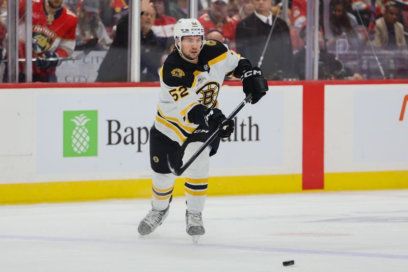 Oct 8, 2024; Sunrise, Florida, USA; Boston Bruins defenseman Andrew Peeke (52) moves the puck against the Florida Panthers during the first period at Amerant Bank Arena. Mandatory Credit: Sam Navarro-Imagn Images