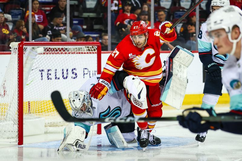 Sep 23, 2025; Calgary, Alberta, CAN; Calgary Flames right wing Matt Coronato (27) and Seattle Kraken goaltender Philipp Grubauer (31) collides during the second period at Scotiabank Saddledome. Mandatory Credit: Sergei Belski-Imagn Images