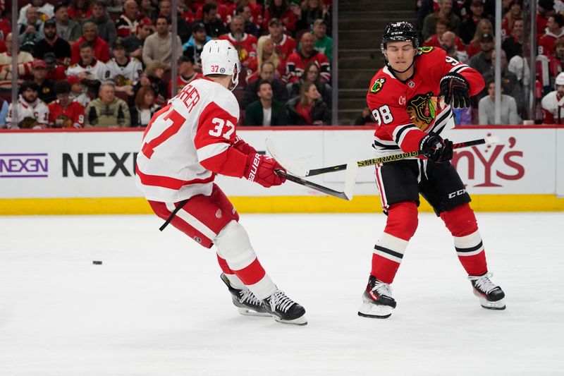 Nov 6, 2024; Chicago, Illinois, USA; Chicago Blackhawks center Connor Bedard (98) and Detroit Red Wings left wing J.T. Compher (37) go for the puck during the second period at United Center. Mandatory Credit: David Banks-Imagn Images