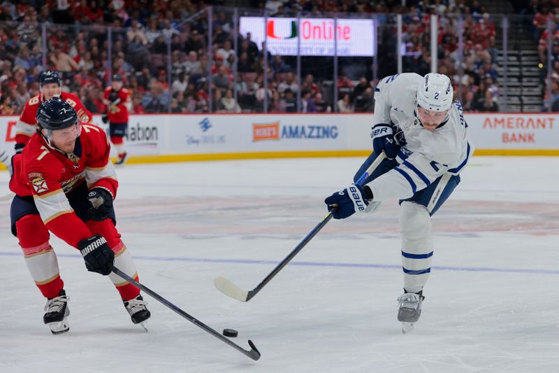 Nov 27, 2024; Sunrise, Florida, USA; Toronto Maple Leafs defenseman Simon Benoit (2) shoots the puck as Florida Panthers defenseman Dmitry Kulikov (7) defends during the second period at Amerant Bank Arena. Mandatory Credit: Sam Navarro-Imagn Images